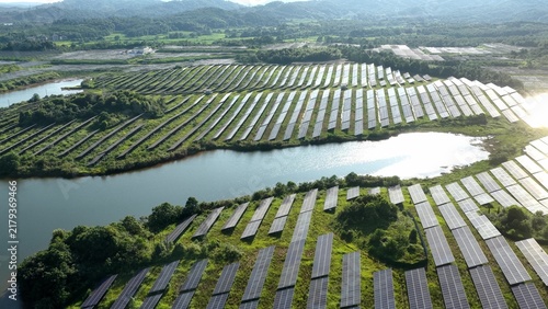 Quadro su tela Solar panel array in green hills and water landscape
