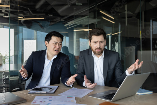 Konstfotografi Two businessmen at an office desk react with frustration and worry as they revie