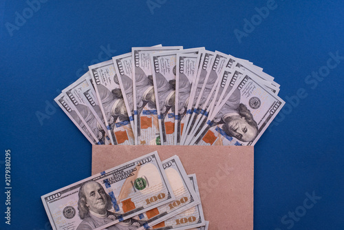 Cuadro en lienzo 100 US Dollar banknotes in and out of a brown craft paper bag on a blue backgrou