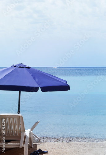 Deck chair with umbrella and slippers on the beach