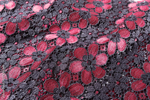 Фотография Black and red floral guipure lace fabric background with metallic sheen