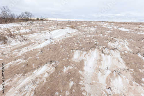 Canvastavla Snow dusted sand dunes stretch toward a distant icy shoreline under an overcast