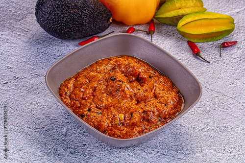 Bild auf Leinwand Spicy red curry paste in gray bowl with avocado, yellow pepper, star fruit, and