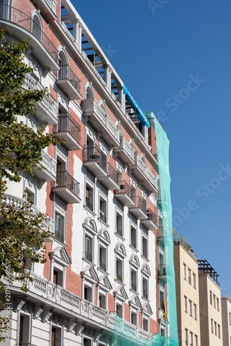 Classic European residential building facade partially covered with green mesh
