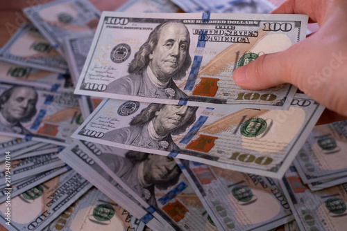 Foto Close-up of a hand counting and holding 100 US Dollar banknotes over a cash background, concept of salary payout, financial transactions, and savings