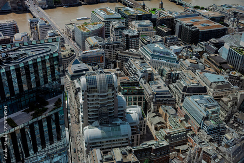 Aerial view over the rooftops of the City of London towards London Bridge and the River Thames on a bright cloudy day.