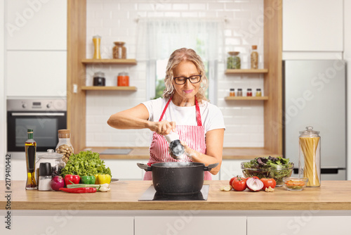 Mature woman cooking and seasoining food