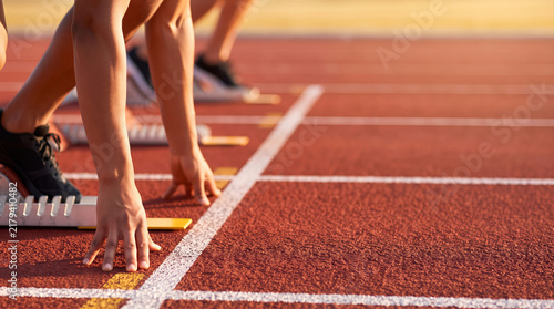 Athletes in starting blocks ready to sprint on red outdoor running track