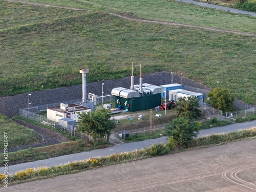Aerial view of the landfill gas utilization plant SkyPoint in Grossziethen with industrial containers and pipes surrounded by fields and a road in Schonefeld, Brandenburg, Germany.