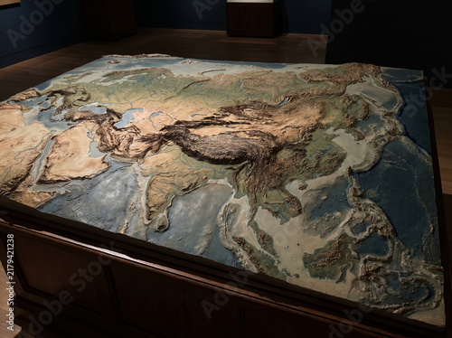 Large three dimensional relief map of Asia displayed on a wooden table in a museum exhibition.