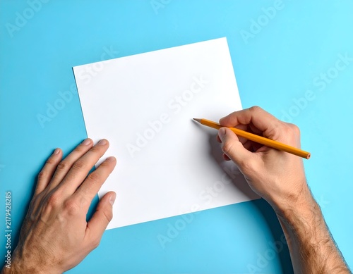 A person's hands holding a pencil above a blank white paper on a blue surface