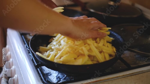 Person putting raw sliced potatoes into frying pan and adding salt video