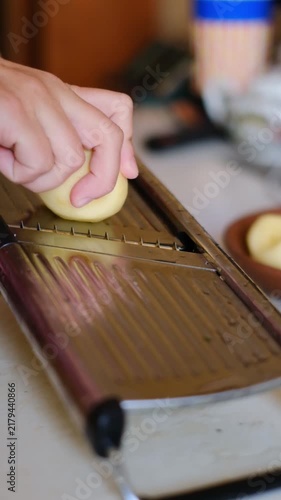 Close up of hand slicing potato with mandoline slicer in kitchen video