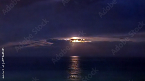 Fotografie Moonlight filtering through stratocumulus beneath an altostratus veil, creating