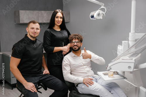 Dental team with satisfied patient in modern clinic