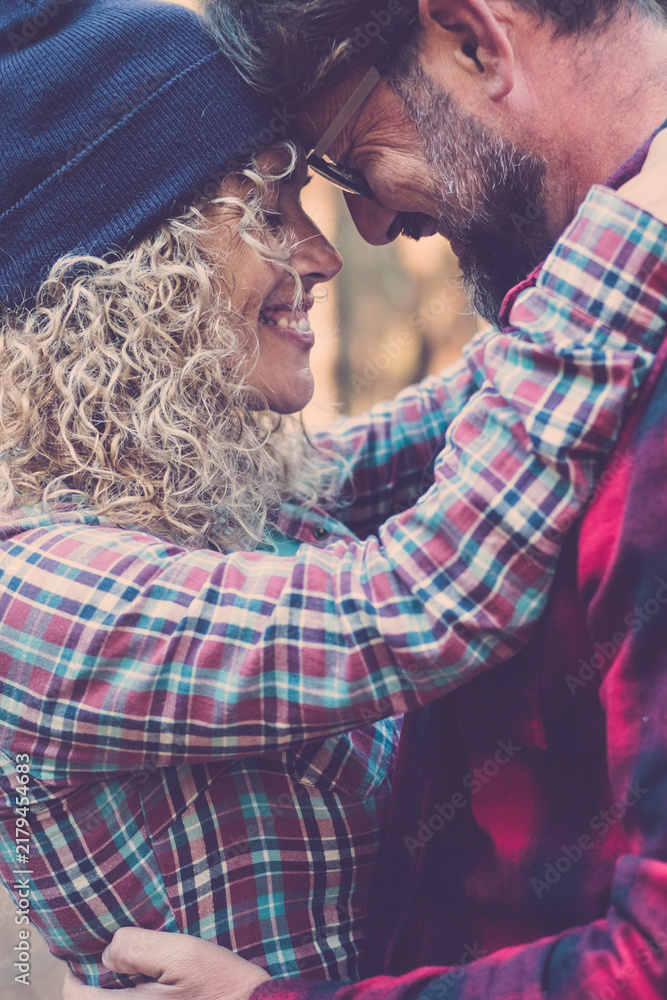 Obraz premium Happy couple embraces, touching foreheads and smiling in a warm autumn forest, sharing an intimate, joyful moment of connection, trust and cozy togetherness