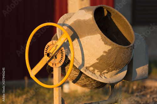 Bild auf Leinwand Portable concrete mixer with yellow handwheel standing on a construction site at