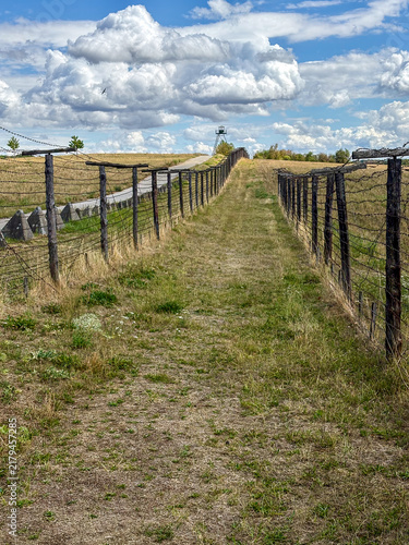 Canvas Print Pathway Through Fenced Field Under Dramatic Clouds