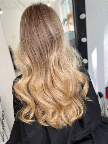 Long wavy balayage blonde hair rear view in salon