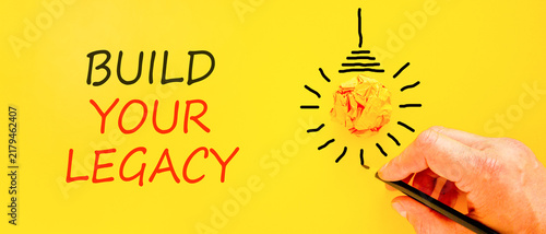 Build your legacy words symbol. Concept words Build your legacy on beautiful yellow paper. Beautiful yellow background. Businessman hand. Business build your legacy concept. Copy space.