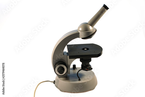 Foto Vintage laboratory microscope with a single eyepiece, black stage, focusing knob and built-in illumination, isolated on a white background