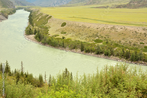 Foto The bed of a wide turquoise river bends along a canyon surrounded by mountain ranges in a picturesque valley on a cloudy summer day