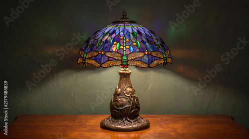 An exquisite stained glass lamp featuring dragonfly designs, casting colorful shadows against a soft background, blending functionality with beautiful artistry in home decor.