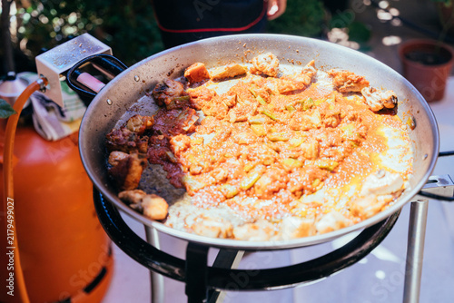 Foto Rustic paella preparation with meat and vegetables simmering outdoors in Mediter