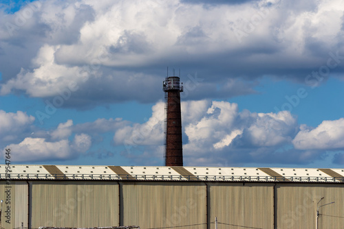 Foto Tall brick industrial smokestack rising against a vibrant blue sky filled with f