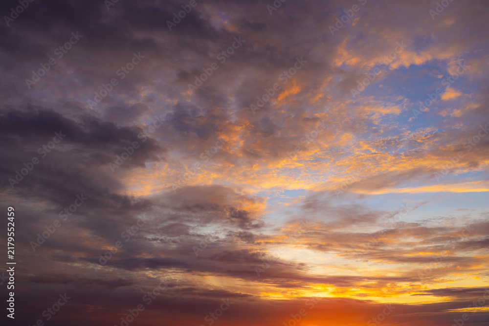 Fototapeta premium Dramatic colorful sunset sky with beautiful clouds,A breathtaking view of a vibrant sunset sky filled with dramatic dark clouds, glowing orange light, and deep purple hues during twilight.