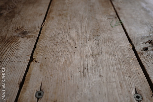Weathered wooden planks with visible grain knots and metal fasteners featuring a shallow depth of field