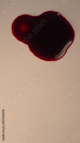 Blood dripping and impacting pool on light surface for crime scene evidence, top view slow motion, bottom copy space, vertical video