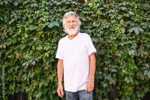 Senior man in the city park having great time close to a vegetable wall
