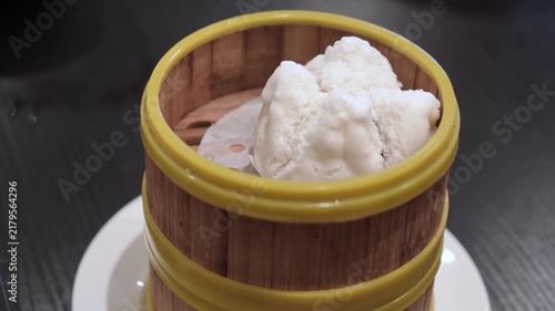 Traditional Chinese char siu bao, or barbecue pork buns, freshly steamed and served in a bamboo steamer with visible steam rising, highlighting its hot and freshly cooked texture.