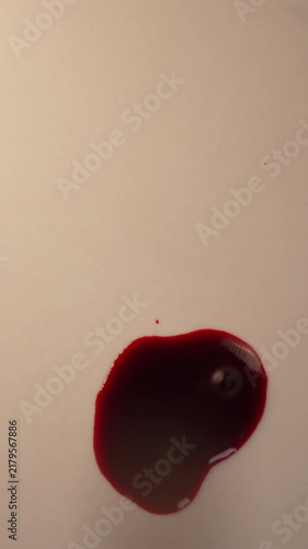 Fresh blood dripping and pooling on light surface for scientific forensic lab analysis, top view zoom in slow motion, top copy space, vertical video