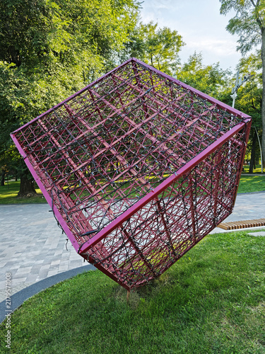 Metallic lattice cube wrapped in garlands in a city park