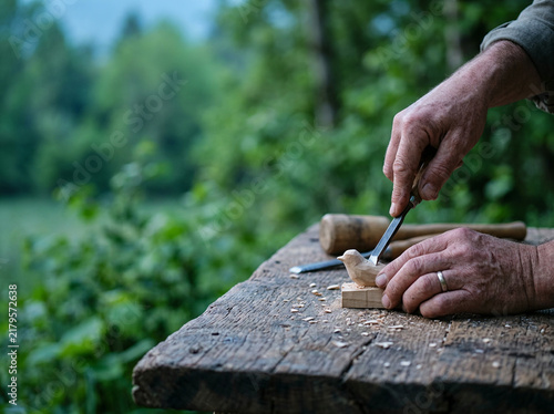 Woodcarver using a chisel and mallet at a rough hewn outdoor workbench