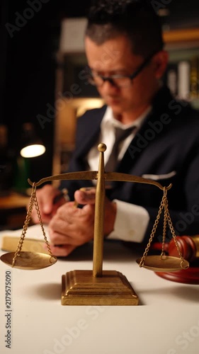 Stressed Lawyer Writing Notes Behind Scales of Justice in Law Office 