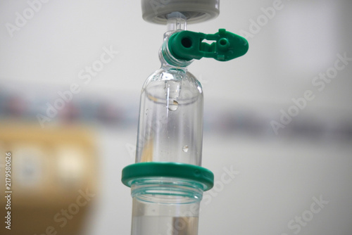 Bild auf Leinwand Close up intravenous drip chamber with saline solution drop in hospital room, medical iv fluid therapy equipment concept for health care and treatment
