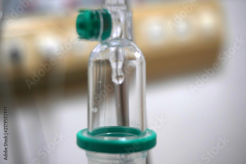 Fotografía Close up intravenous drip chamber with saline solution drop in hospital room, medical iv fluid therapy equipment concept for health care and treatment