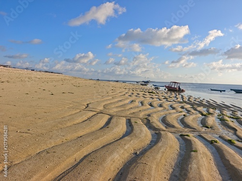 Canvastavla Tropical sandy beach at low tide with natural ripple patterns, calm blue sea, pa