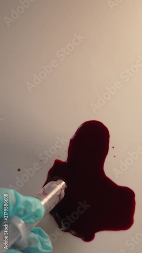 Extracting blood sample with tube for crime scene investigation and lab analysis, top view slow zoom in, top copy space, vertical video