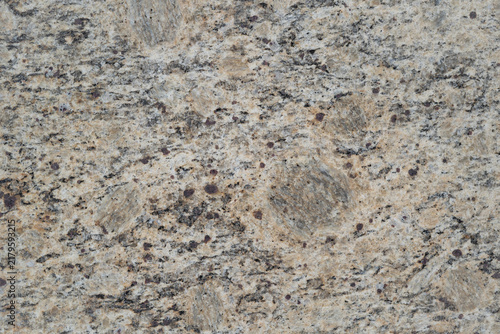 Full frame background texture of natural beige and grey granite stone surface with mineral speckles
