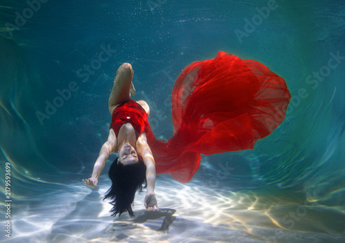 Foto Calm and relaxed young girl in elegant young woman floating in a tranquil underwater environment