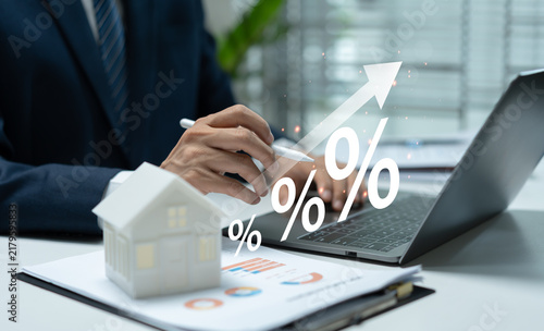 Canvastavla Businessman reviewing rising interest rates with house model, laptop, and financial report, illustrating mortgage costs, housing finance, property investment, and economic growth