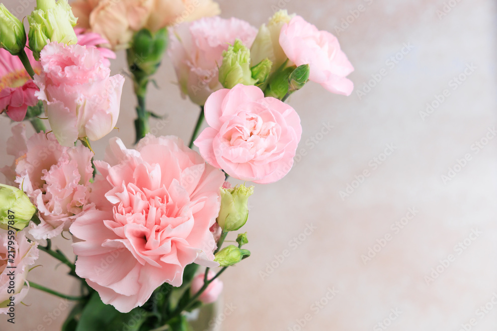 Fototapeta premium Pink flowers in a simple vase placed on a light background during daylight