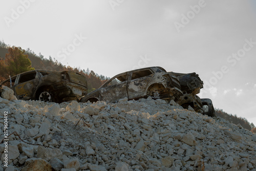 Obraz na płótnie Burned out cars resting on rocky hillside under hazy sky