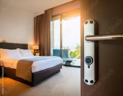 modern electronic smart lock on a hotel room door with a blurred bedroom background in warm sunlight security concept for hospitality and travel