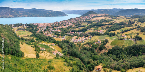 фотографія Bright summer aerial panorama of a riverside town nestled among rolling green hills along a wide Danube river winding through forested valleys