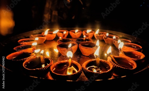 Cuadro en lienzo A close-up shot of multiple traditional earthen oil lamps, known as Diya, beautifully illuminated and arranged on a metallic tray in the dark